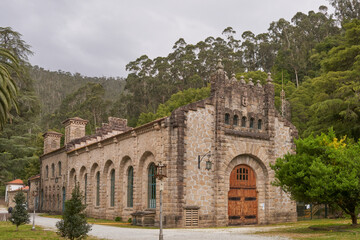 Fototapeta na wymiar large stone building among nature. it is an hydroelectric plant at the tambre river in noia, galicia