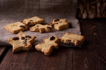 Healthy homemade gluten-free, lactose-free cookies of various shapes without sugar with raisins and chocolate on a dark brown wooden background