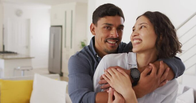 Portrait of happy romantic hispanic couple embracing in living room