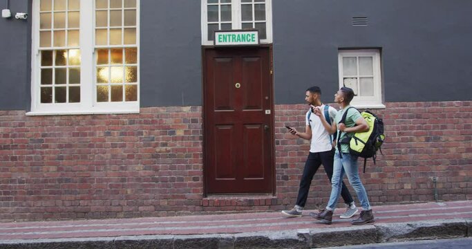 Two mixed race male friends walking and looking for hostel in the street