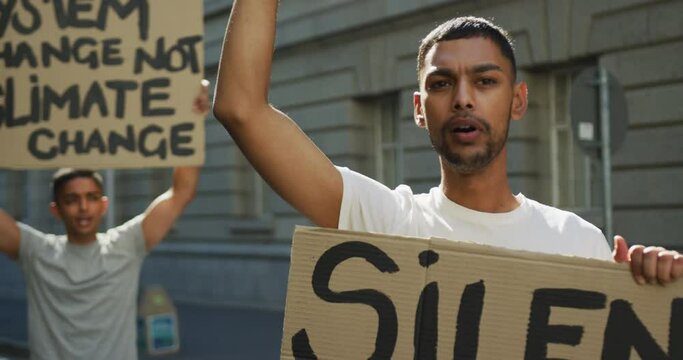 Two mixed race men on a protest march holding placards raising hands and shouting