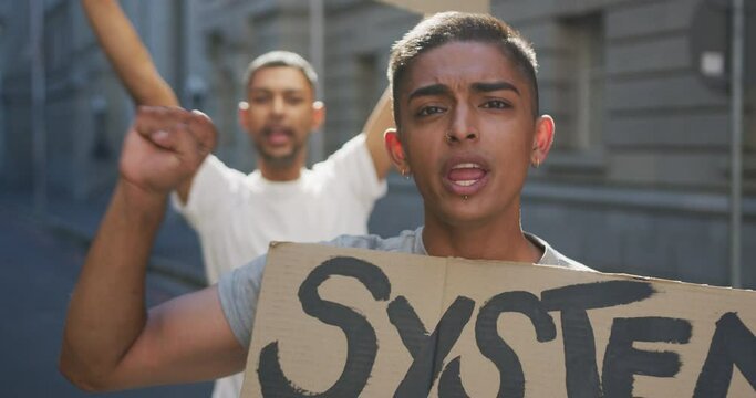 Two mixed race men on a protest march holding placards raising hands and shouting