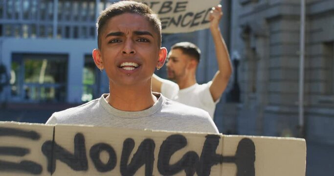 Two mixed race men on a protest march holding placards raising hands and shouting