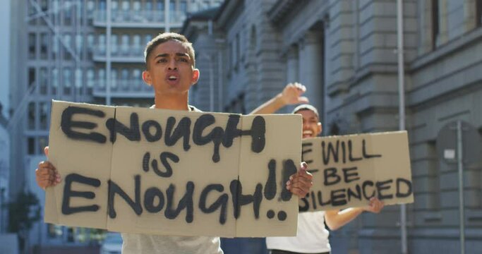 Two mixed race men on a protest march holding placards raising hands and shouting