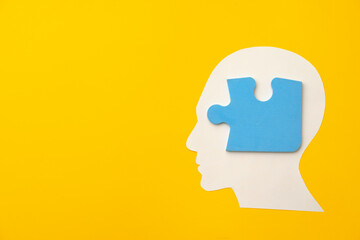 Papercut head silhouette with puzzle pieces on yellow background