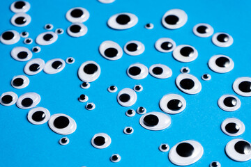 Toy eyes of different sizes scattered on a blue background