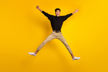 Fototapeta na wymiar Photo of cute funny dark skin guy dressed black pullover jumping high like star isolated yellow color background