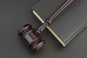 Judge gavel and black book on black table, top view