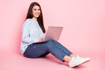 Full size photo of young happy cheerful smiling girl sit floor browsing in computer isolated on pink color background