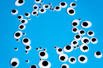 Toy eyes of different sizes scattered on a blue background