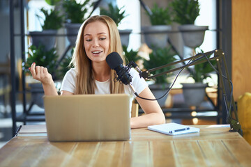 Front view of young attractive woman telling interesting information with modern microphone in live...