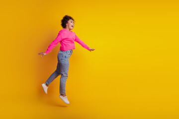 Fototapeta na wymiar Profile portrait of active sporty girl jumping isolated on yellow background
