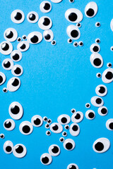 Toy eyes of different sizes scattered on a blue background