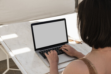 Young woman workin on laptop computer on marble table with sunlight shadows. Work at home concept. Girl boss, lady boss business composition for blog, web, social media. Blank mockup copy space screen