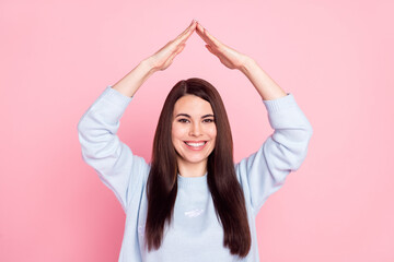 Naklejka premium Photo of pretty sweet young lady dressed blue sweater smiling showing arms roof isolated pink color background