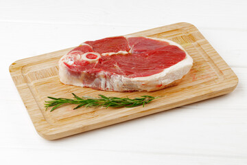 Fototapeta na wymiar Raw lamb steak on board on white wooden table