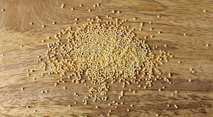 Peeled yellow millet seeds on wooden board background and texture, top view
