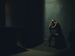 woman sitting on a chair in a dark room loneliness falling light silhouette