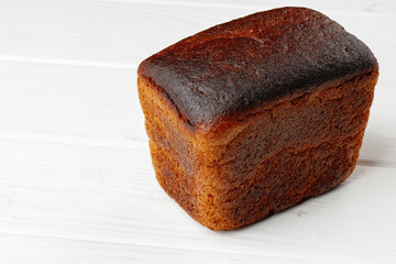 Loaf of rye bread on white wooden table