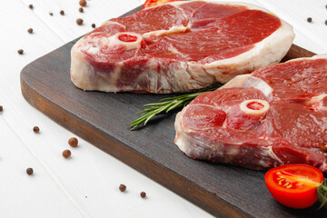 Raw lamb steak on board on white wooden table