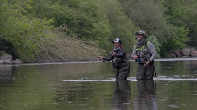fishing guide with a young woman fly fishing for trout in a clear river