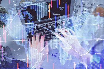 Double exposure of man's hands typing over computer keyboard and business theme hologram drawing. Top view. Financial markets concept.