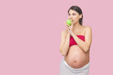 young pregnant woman bites a green apple