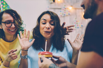 Cropped image of funny female blowing candle for make birthday wish come true on excited party,...