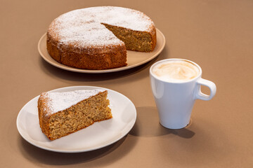 A cup of fresh cappuccino and a piece of cake made from almonds and dry bread (Antica torta alle mandorle e pane)