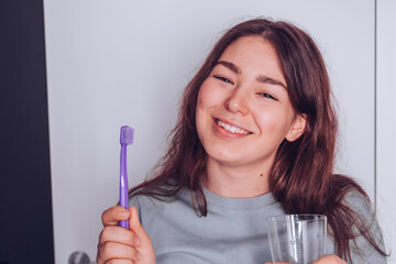 Young cheerful girl holding toothbrush and smiling. Morning routine concept