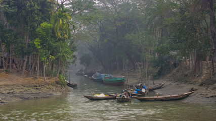 Fototapeta na wymiar Landscape view in the morning haze of fishing boats on the water in green environment, Mehendiganj, Barisal, Bangladesh