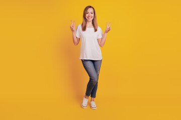 Fototapeta na wymiar Young girl show victory sign isolated on yellow background