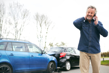 Senior Male Driver With Whiplash Calls Car Insurance Company On Mobile Phone After Traffic Accident