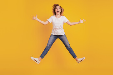 Fototapeta na wymiar Smiling excited crazy funky girl jumping open mouth on yellow background