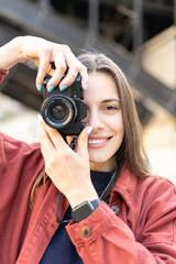 Portrait of a lively femail phototgrapher taking picture on the vintage camera with a smile, and still looking with one eye in to the frame