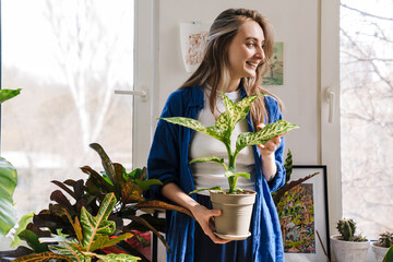 Young woman florist taking care of pot plants