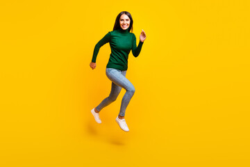 Fototapeta na wymiar Full size photo of nice optimistic brunette lady jump wear green sweater jeans sneakers isolated on bright yellow color background