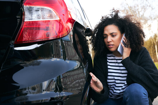 Female Driver In Car Park Calling Insurance Company On Mobile Phone To Report Vandalism Damage
