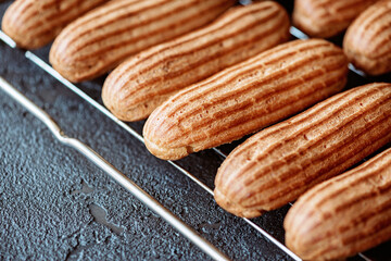 French pastry dessert eclair. Freshly baked aromatic custard cakes cool on the wire rack. Soft selective focus.