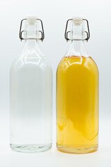 two glass bottle containing tea and clear water isolated on white background