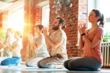 Tuinposter fitness, yoga and healthy lifestyle concept - group of people doing lotus seal gesture and meditating in seated pose at studio © Syda Productions