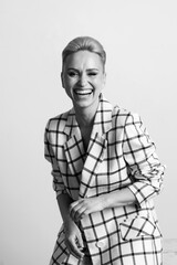 Elegant ant charismatic blond and short haired women with beautiful wide smile wearing oversized linen suit posing isolated in studio. Black and white version..