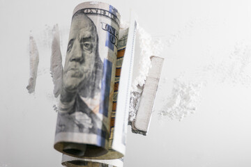 A pile of white drugs witha razor blade and US currency rolled up for snorting.