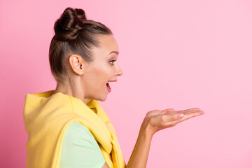 Photo of funny impressed young lady dressed green t-shirt holding arms empty space isolated pink color background