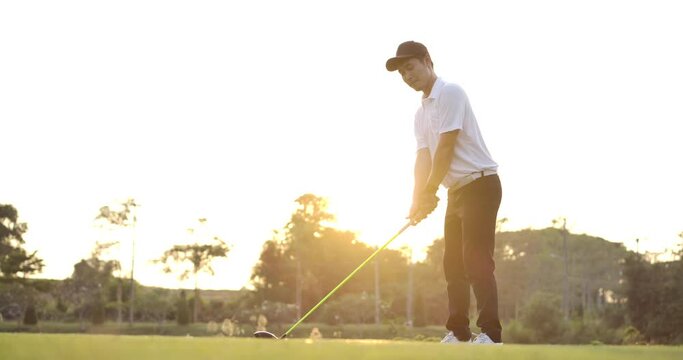 Asian male golfer holding driver watching his ball after teeing off on fairway and celebrates in slow motion.