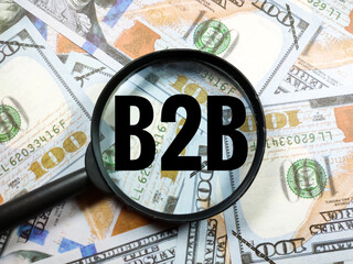 Business concept.Text B2B (Business to business) with magnifying glass on dollar banknote background.