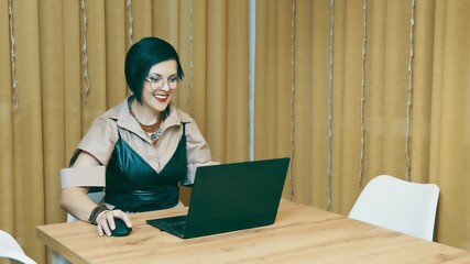 Successful woman working remotely at home. The freelancer opens a nice top and enjoys working at home. A business lady works on a laptop and demonstrates positive emotions while working at a computer.