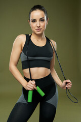 Charming young woman with skipping rope posing in studio