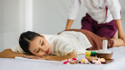 Obraz na płótnie Canvas beautiful Thai woman enjoy getting a massage happily in a spa. Relaxing and healing with Thai massage. Body care and treatment, alternative medicine concept