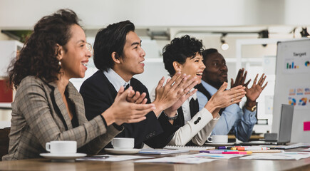 Business men and women of different nationalities were clapping their hands happily and smiling. In the meeting room at the office. Concept diversity meeting happy smilling.